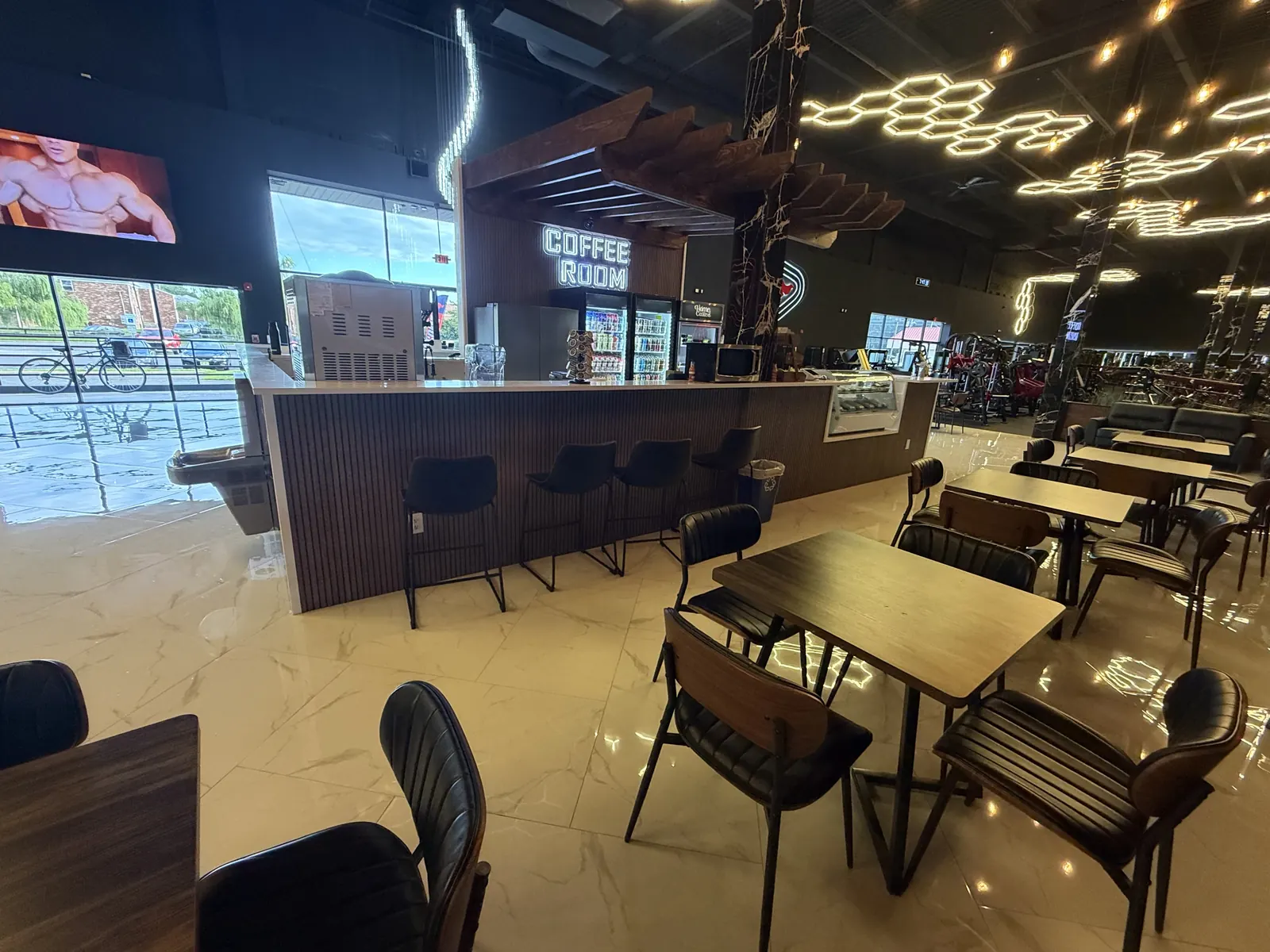Coffee room seating with wood tables and bar stools beside the gym floor
