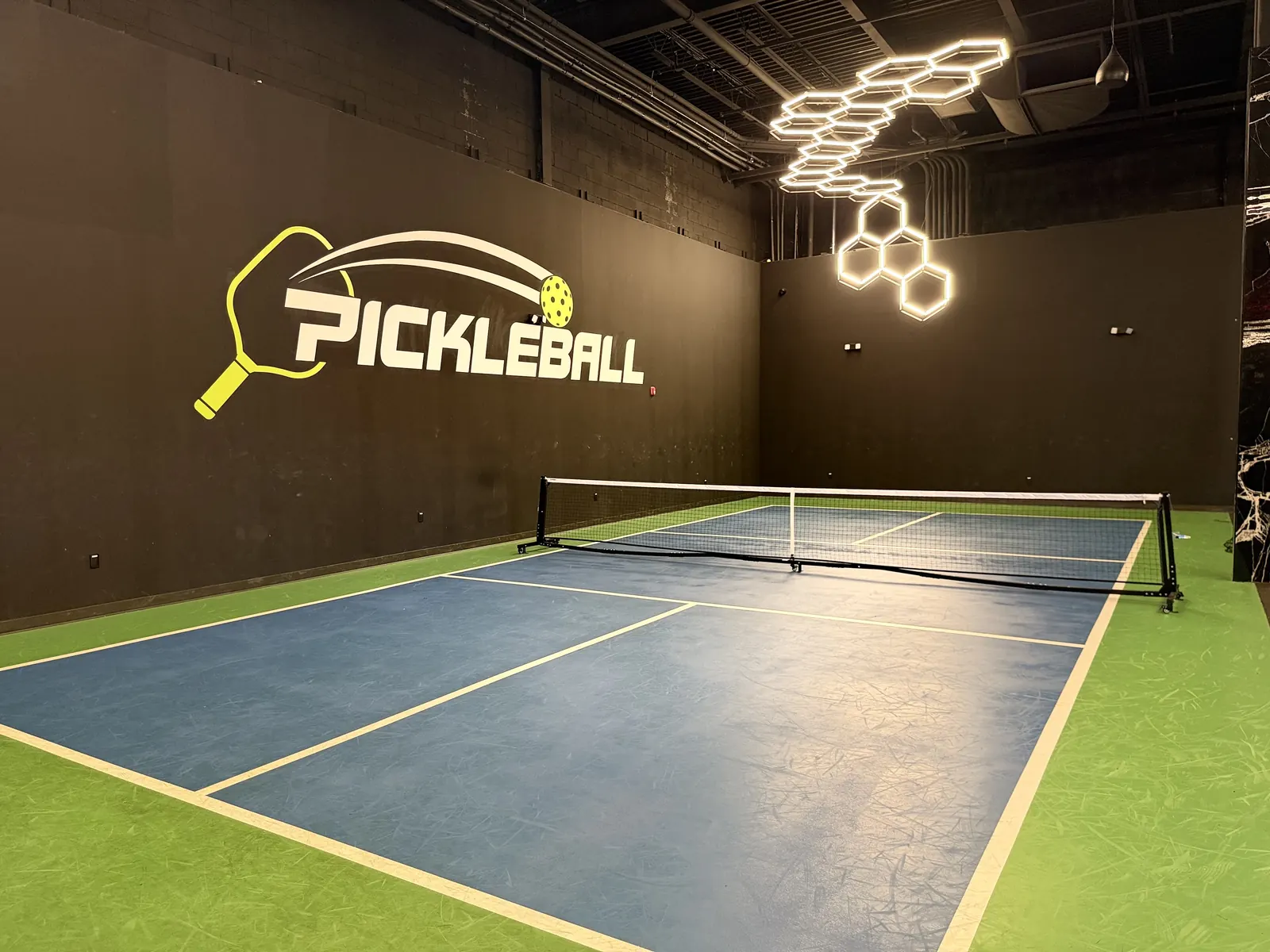 Indoor pickleball court with a net and painted court lines