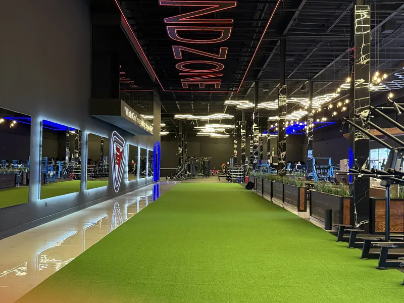 Indoor turf lane under a red ENDZONE sign, the weight floor beyond